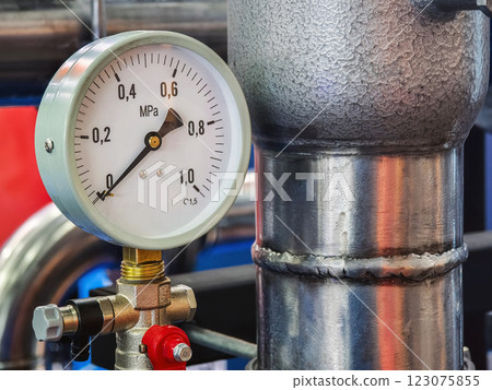 Pressure gauge indicating measurement near metallic pipeline in industrial facility 123075855