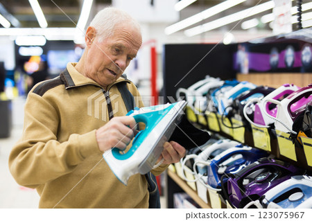Senor man pensioner buying iron in showroom of electrical appliance store Senor man pensioner buying iron in showroom of electrical appliance store 123075967