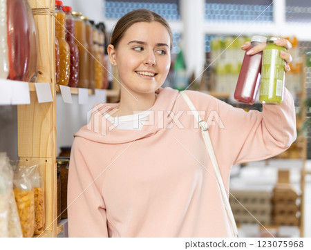 Female shopper chooses bottle of smoothie while shopping in supermarket Female shopper chooses bottle of smoothie while shopping in supermarket 123075968