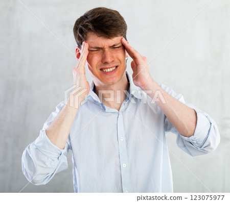 Young guy holding on to his sore head Young guy holding on to his sore head 123075977