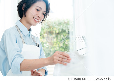 A woman drying clothes in a room 123076310