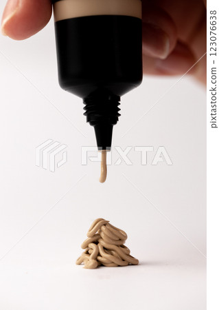 Sleek Beauty Product in Action: A Close-Up View of Foundation Dripping from a Tube to Create an Intriguing Design on a White Background 123076638