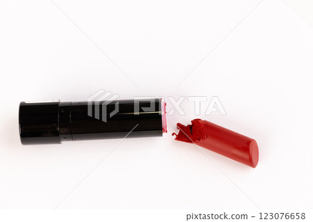 A Broken Red Lipstick in Black Tube Captured on a Clean White Background - A Close Up View of Beauty Product Disarray and Lip Color. A Broken Red Lipstick in Black Tube Captured on a Clean White Background - A Close Up View of Beauty Product Disarray and Lip Color. 123076658