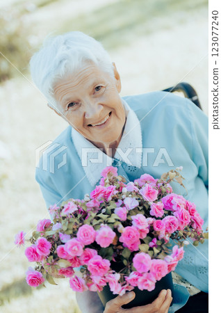 Portrait of smiling senior woman holding a purple flower pot outdoors Portrait of smiling senior woman holding a purple flower pot outdoors 123077240