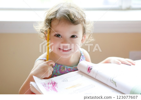 Little toddler girl writing at school desk 123077607