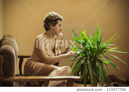 Girl with a green plant in a cozy, sun-filled space on a calm day 123077706