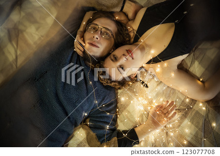 Couple enjoying intimate moments surrounded by warm fairy lights in a cozy setting Couple enjoying intimate moments surrounded by warm fairy lights in a cozy setting 123077708