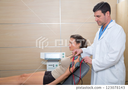 Doctor therapist checking muscle electrostimulation to woman 123078143