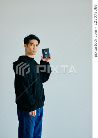 一名二十多歲的年輕人拿著護照 123078369