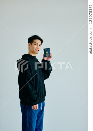 A young man in his twenties holding a passport 123078375