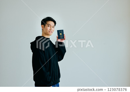 A young man in his twenties holding a passport A young man in his twenties holding a passport 123078376