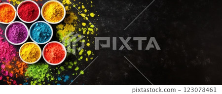 Small white bowls filled with vibrantly colored Holi powders arranged on a dark, textured background. 123078461