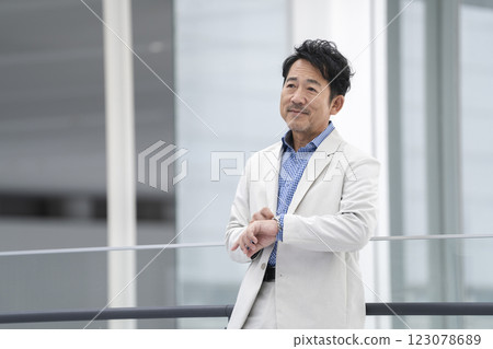 A man in his mid-50s wearing a white suit 123078689