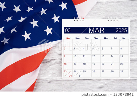 March 2025 Monthly desk calendar and United States of America flag. 123078941