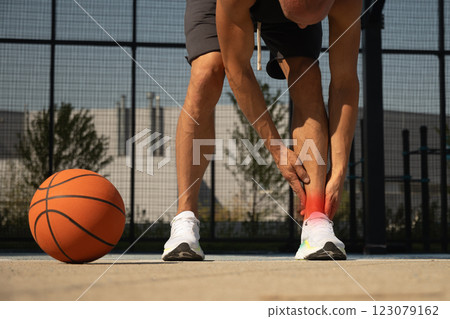 Basketball ankle injury or pain. Basketball player check legs after workout of sport stadium. Professional athlete or sportsman with accident. Man check pain in leg after sport workout. 123079162