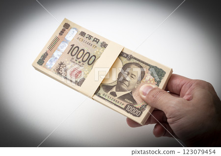 手拿著一疊 100 萬日圓的鈔票 123079454