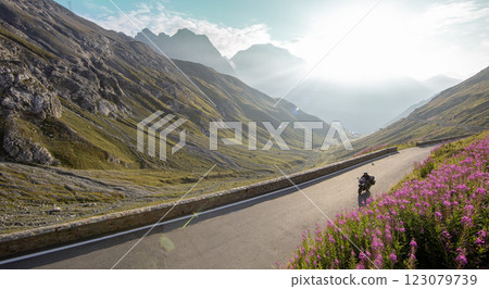Motorbiker riding in Italian Alps during sunrise, dramatic sky. Travel and freedom, outdoor activities Motorbiker riding in Italian Alps during sunrise, dramatic sky. Travel and freedom, outdoor activities 123079739