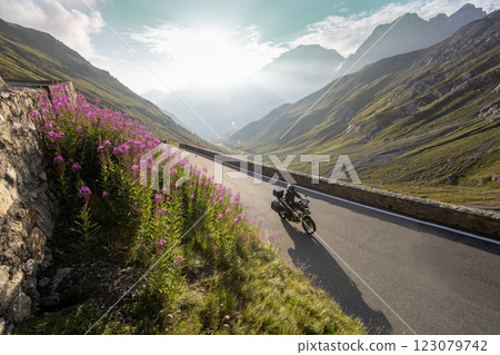 Motorbiker riding in Italian Alps during sunrise, dramatic sky. Travel and freedom, outdoor activities 123079742