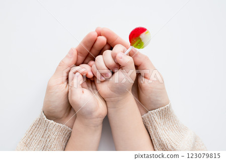 Childs hand holding lollipop with adult supportive hands 123079815