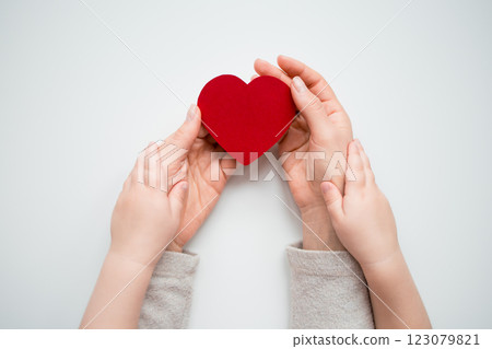 Adult and child holding red heart symbolizing love and care 123079821