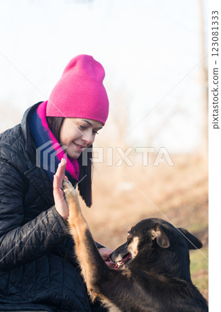 Woman in hat in park teaches dog to give high five, close-up Woman in hat in park teaches dog to give high five, close-up 123081333