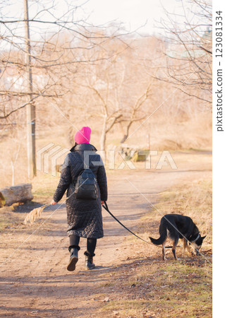 Woman in hat and coat walking with dog, photo from the back Woman in hat and coat walking with dog, photo from the back 123081334