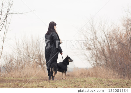 Woman walking her dog in the park on a cloudy day Woman walking her dog in the park on a cloudy day 123081584
