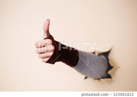 A woman's hand in a knitted burgundy mitten shows a gesture good A woman's hand in a knitted burgundy mitten shows a gesture good 123081822