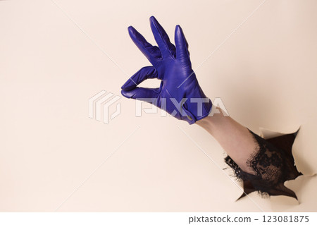 A woman's hand in a leather blue glove shows a gesture okay A woman's hand in a leather blue glove shows a gesture okay 123081875