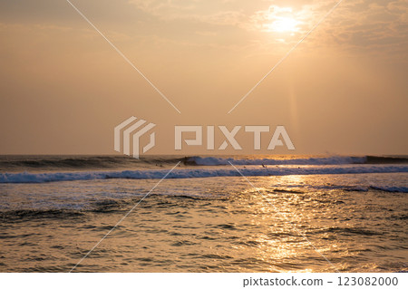The ocean is calm and the sun is setting, creating a peaceful and serene atmosphere 123082000