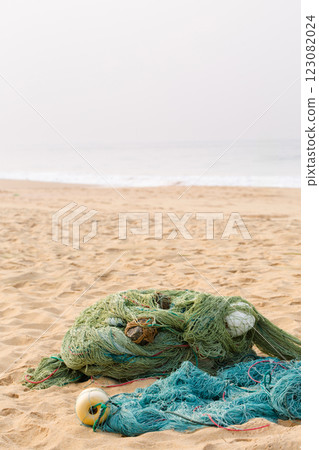Green net with large floats lies on the shore, with ocean in the background Green net with large floats lies on the shore, with ocean in the background 123082024