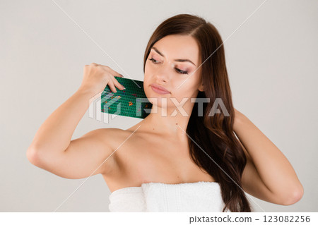 A beautiful brunette in a white towel applies a needle applicator to her neck. A beautiful brunette in a white towel applies a needle applicator to her neck. 123082256