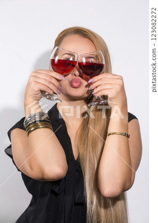 A woman with long blonde hair is holding two wine glasses A woman with long blonde hair is holding two wine glasses 123082272