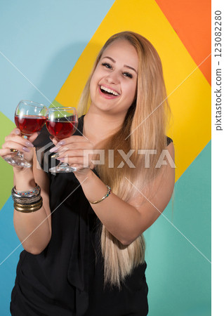 Cheerful blonde woman holding two glasses of red wine and smiling. Holiday concept 123082280