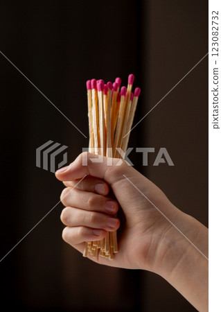 A hand holding a bunch of matches with a pink and red tip A hand holding a bunch of matches with a pink and red tip 123082732