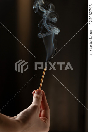 A woman's hand holds a long match that is extinguished and smoking A woman's hand holds a long match that is extinguished and smoking 123082748