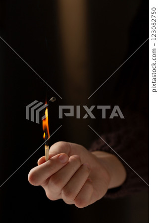 Hand holding a lit match. Concept of warmth and comfort as a person holds a match to light a candle or fire 123082750