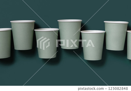 Disposable light green paper cups on a dark green top view, mockup. Sustainable lifestyle 123082848