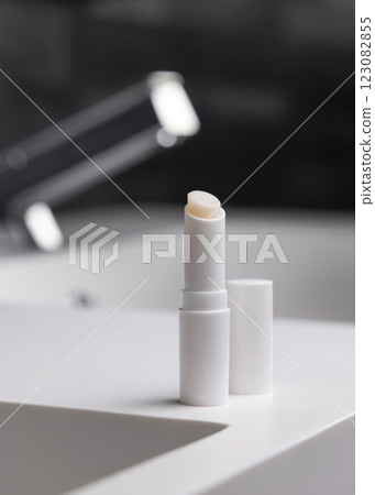 Lip balm stick with blank lid on basin in dark grey modern bathroom close up, cosmetic mockup Lip balm stick with blank lid on basin in dark grey modern bathroom close up, cosmetic mockup 123082855
