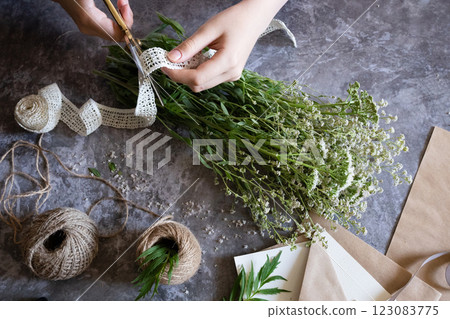 Creating a rustic floral arrangement with natural materials on a textured surface in a cozy crafting space Creating a rustic floral arrangement with natural materials on a textured surface in a cozy crafting space 123083775