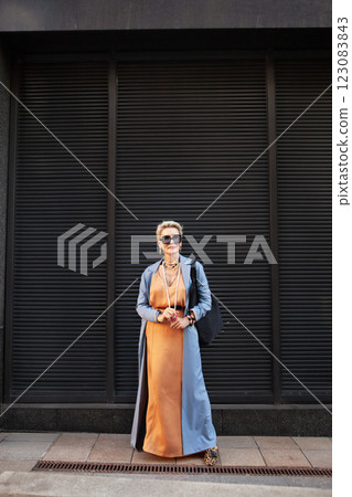 Stylish Mature Woman Standing City Street In Fashionable Clothes, Wearing Long Beige Silk Dress, Blue Coat Stylish Mature Woman Standing City Street In Fashionable Clothes, Wearing Long Beige Silk Dress, Blue Coat 123083843
