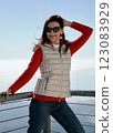 Satisfied woman 51 years old in a sporty outfit and sunglasses posing against the backdrop of mountains and blue sky Antalya Turkey 123083929
