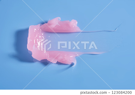 The texture of a pink lip mask or balm on a blue background. The texture of a pink lip mask or balm on a blue background. 123084200