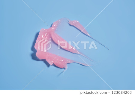 The texture of a pink lip mask or balm on a blue background. The texture of a pink lip mask or balm on a blue background. 123084203
