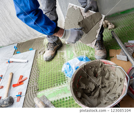 Tiler at work installing new floor with tiles. Construction. Tiler at work installing new floor with tiles. Construction. 123085104