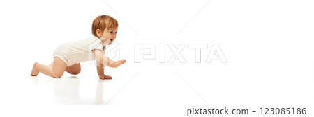 Banner. Baby in onesie crawling forward with joyful expression and arm extended against white background with negative space. 123085186