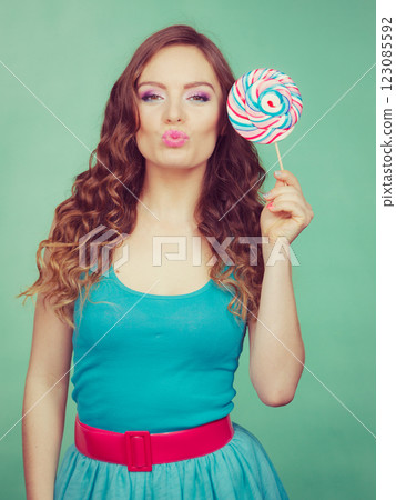Smiling girl with lollipop candy on teal 123085592