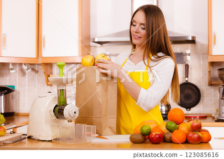 Woman in kitchen preparing fruits for juicing 123085616