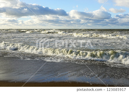 Scenic Baltic sea coastal seascape, stormy sea with big waves, cloudy dark sky, sandy beach 123085917