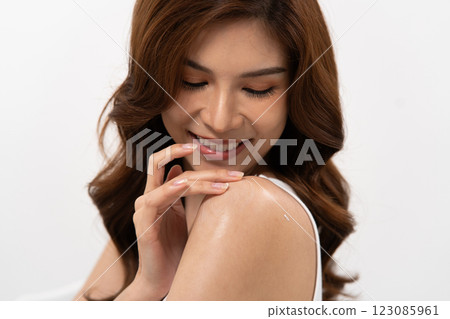 Smiling beauty with glowing skin showcasing skincare routine in a bright setting 123085961